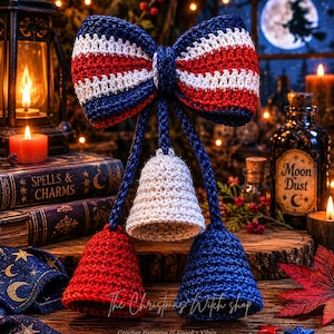 May include: A crochet decoration featuring a large bow with horizontal stripes in navy blue, white, and red. Three crocheted bells hang from the bow by braided cords, with one white bell in the center flanked by a red bell and a navy blue bell.