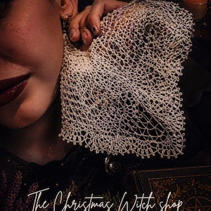 Op de afbeelding: Een witte kanten zakdoek wordt dicht bij het gezicht van een persoon gehouden. De afbeelding bevat de tekst "Witch's Veil Lace Handkerchief" en "The Christmas Witch shop". De zakdoek heeft een delicaat, open geweven ontwerp.