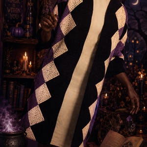 May include: A long, open-front cardigan with a geometric pattern. The cardigan features black, purple, and cream-colored diamond shapes. The background includes a bookshelf with books, candles, and a cauldron, suggesting a mystical theme.