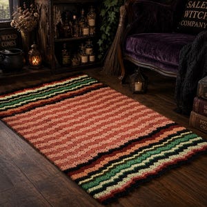 May include: A rectangular crochet rug featuring a wide central section of variegated peach and coral yarn, bordered by wavy stripes in black, dark green, and light green. The textured, handmade textile displays a consistent ripple pattern throughout.