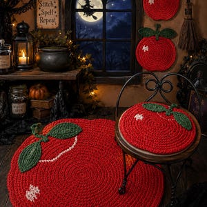 May include: A set of three round, red, crocheted apple-shaped items with green leaves and white stitched accents. The collection includes a large circular floor rug, a smaller circular seat cushion, and two smaller wall-hanging decorations.
