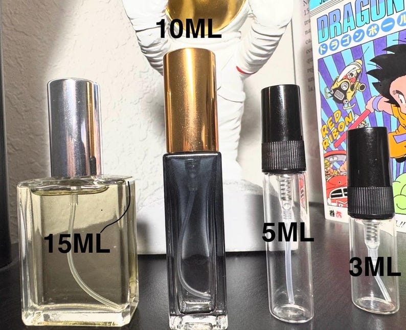 May include: Four perfume bottles of varying sizes: 15ml, 10ml, 5ml, and 3ml. The 15ml bottle is square with a silver cap. The 10ml bottle is rectangular with a gold cap. The 5ml and 3ml bottles are clear with black caps. The bottles are for fragrance samples.