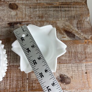 May include: A white star-shaped ceramic dish with a smooth finish. A metal ruler is placed across the center, showing a diameter of approximately 3.5 inches. The dish features five distinct points and a central basin for holding small items.