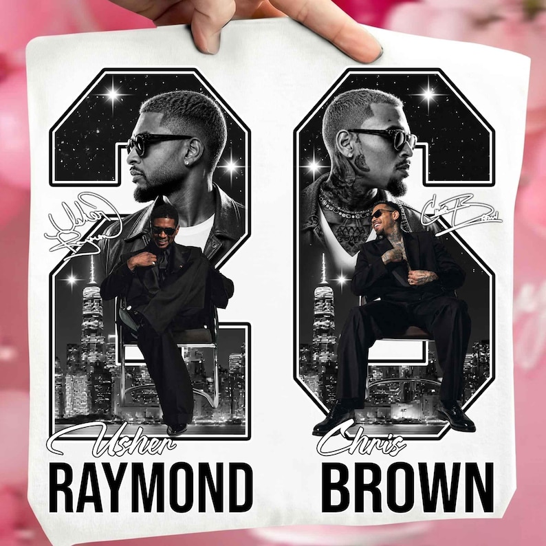 May include: A white t-shirt featuring a graphic design with two large black numbers 2 and 6. Inside the numbers are black and white portraits of Usher and Chris Brown, city skylines, and star-filled skies. The names Usher Raymond and Chris Brown are printed below.