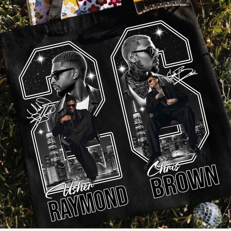 May include: A black tote bag featuring a graphic print of two large white outlines of the number 22. Inside the outlines are black and white portraits of Usher and Chris Brown, city skylines, and their printed names and signatures in white.