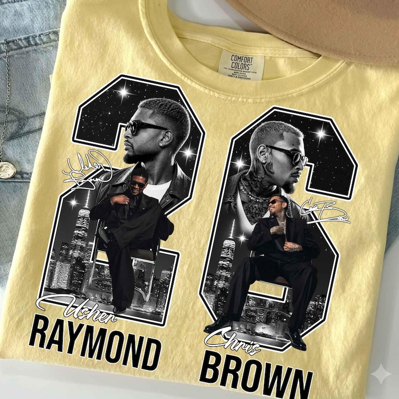 May include: A pale yellow t-shirt featuring a graphic print of two black and white portraits of Usher Raymond and Chris Brown. Each portrait is framed within a large number, with city skylines, star patterns, and signatures included in the design.