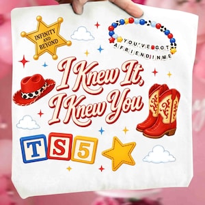 May include: A white tote bag featuring a graphic print with the text I KNEW IT, I KNEW YOU. The design includes a yellow sheriff star with INFINITY AND BEYOND, a beaded bracelet with YOU'VE GOT A FRIEND IN ME, a red cowboy hat, red boots, and blocks with TS5.