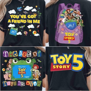 Pode incluir: Uma t-shirt preta com gr&aacute;ficos de Toy Story. Um lado exibe o texto "YOU'VE GOT A FRIEND IN ME" com nuvens e estrelas. Outro lado mostra uma mochila roxa cheia de personagens e "TOY STORY 5". Outros designs incluem uma moldura de sapo com "TOY STORY 5" e o texto "THE AGE OF TOYS IS OVER".
