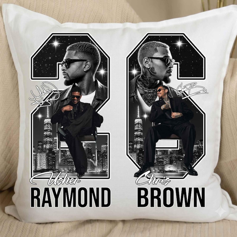 May include: A white square throw pillow featuring a black and white graphic design. The print displays two large numbers, 2 and 6, framing portraits of Usher Raymond and Chris Brown. Each artist is shown in a suit, with city skylines and text below.