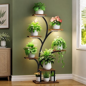 May include: A tall, black metal plant stand with multiple wooden shelves arranged in a branching design. The stand features integrated LED lights under several shelves, illuminating various potted plants in white ceramic pots of different sizes.