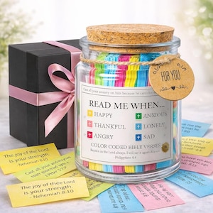 May include: A glass jar filled with colorful Bible verses, topped with a cork lid and a "For You" tag. A black gift box with a pink ribbon sits beside the jar. The jar contains color-coded verses for different emotions.