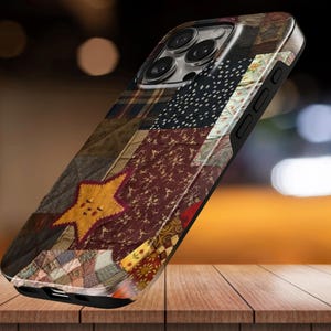 Op de afbeelding: Een smartphonehoesje met een patchwork quiltontwerp met diverse stoffen, waaronder een opvallende gele ster, donkerrode bloemenprints, zwart-witte stippen en ruitjespatronen, met uitsparingen voor de cameralens en de knoppen aan de zijkant.