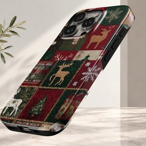 May include: A smartphone case featuring a festive patchwork pattern with alternating squares of deep red and dark green. The design includes gold-toned reindeer silhouettes, white snowflakes, evergreen trees, and gift boxes, creating a holiday-themed aesthetic.