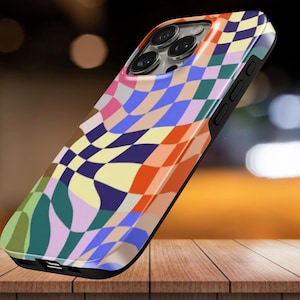 May include: A smartphone case featuring a multi-colored, distorted checkerboard pattern in shades of orange, blue, pink, green, and yellow. The case has a black frame and cutouts for the camera lenses, side buttons, and charging port.