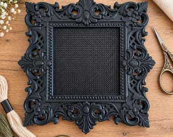 May include: A square black frame featuring an intricate, ornate relief pattern with scrolling foliage and floral motifs. The center of the frame contains a fine black mesh grid, surrounded by a beaded inner border detail.