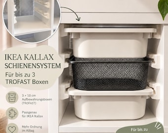 May include: A white plastic rail system installed inside a white shelving unit, designed to hold up to three storage bins. The system includes two white plastic bins and one black metal mesh basket, with text reading IKEA KALLAX SCHIENENSYSTEM.