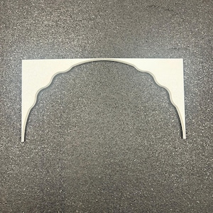 May include: A flat, off-white decorative arch piece featuring a scalloped, curved inner edge and straight outer vertical sides. The object is composed of two symmetrical halves joined at the center, creating a wide, continuous arched opening.