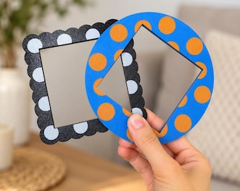 May include: Two small mirrors with decorative frames. One mirror has a square shape with a black scalloped border featuring white polka dots. The second mirror is circular with a bright blue frame decorated with orange polka dots.