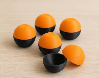 May include: A set of five spherical containers, each featuring a vibrant orange top half and a matte black bottom half. One of the spheres is separated into two distinct pieces, revealing a hollow black interior, while the others remain closed.