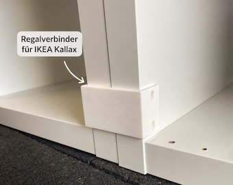May include: A white plastic shelf connector designed for IKEA Kallax shelving units. The rectangular component features two circular screw holes on the side and is shown attached to the vertical panels of a white shelf unit with the text Regalverbinder für IKEA Kallax.