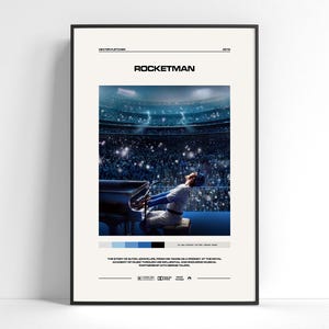 May include: A framed film poster for Rocketman featuring a central image of a performer at a piano in a stadium. The poster includes the title, director Dexter Fletcher, the year 2019, a colour palette, and a summary of the film's plot in black text.