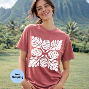 May include: A red t-shirt with a white floral design. The design features four round shapes with dotted textures, surrounded by white leaves. The shirt is made of soft material and is suitable for casual wear.