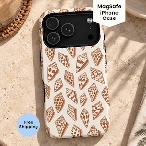 Peut inclure: Une coque MagSafe pour iPhone avec un motif répétitif d'illustrations de coquillages marron sur fond crème. La coque présente une zone de découpe noire pour l'appareil photo, une étiquette blanche MagSafe iPhone Case et un cercle bleu Free Shipping.