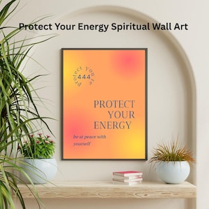 Könnte beinhalten: Ein gerahmter Wandkunstdruck mit dem Text "Protect Your Energy" in Marineblau auf einem orange-gelben Farbverlaufshintergrund. Der Druck enthält auch den Text "be at peace with yourself". Das Kunstwerk wird auf einem Holzregal mit Pflanzen und Büchern ausgestellt.