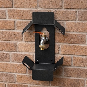 Puede incluir: Soporte de manguera de metal negro montado en una pared de ladrillos. El soporte tiene un grifo plateado con manija de latón y un estante. La pared de ladrillos es de color marrón y beige.