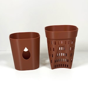 May include: Two brown plastic plant pots. One is a solid, rectangular shape with a teardrop-shaped cutout. The other is a brown, perforated pot with a flared, rectangular shape. Both pots are empty and sit on a white surface.