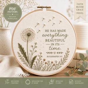 May include: A circular embroidery hoop containing a cream-coloured fabric with a stitched dandelion design. The text reads: HE HAS MADE everything BEAUTIFUL IN ITS time. ECCLESIASTES 3:11. The embroidery features green stems, leaves, and white seeds.