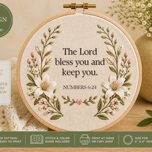 Puede incluir: Arte de aro bordado con el texto "The Lord bless you and keep you" de Números 6:24, rodeado de bordados florales en blanco, rosa y verde. Parte de la colección Wildflower Scripture.