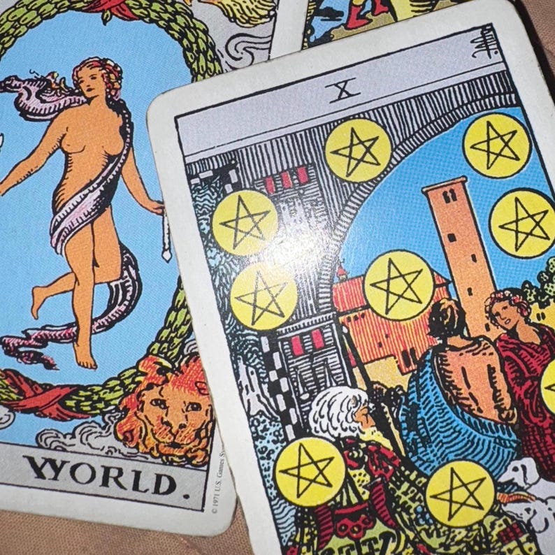 May include: Two tarot cards are shown. One card features a nude figure with a white sash, surrounded by a blue background and the word "WORLD." The other card shows a scene with figures, a tower, and yellow pentacles.