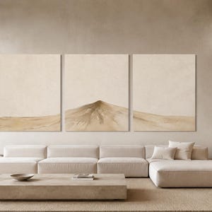 Könnte beinhalten: Ein modernes Wohnzimmer mit einem beigefarbenen Ecksofa, einem rechteckigen Couchtisch und drei großen abstrakten Gemälden mit einem Wüstenlandschaftsthema. Der Raum hat eine neutrale Farbpalette und natürliches Licht.