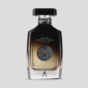 May include: A rectangular perfume bottle with a black cap and a silver label that reads "Absolute Noir". The bottle has a gradient from black to gold and features a silver emblem with the letter "A". The bottom of the bottle is clear.