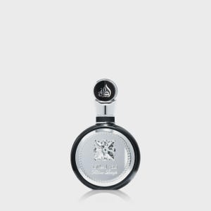 May include: A black and silver perfume bottle with a round shape and a silver cap. The bottle has a silver label with Arabic script and the words "Fabien Lengfe". The cap is black with a silver design.