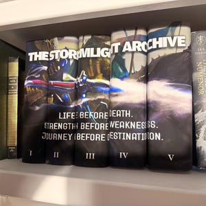 Puede incluir: Una estanter&iacute;a exhibe una colecci&oacute;n de libros de tapa dura. El enfoque principal est&aacute; en una serie titulada "THE STORMLIGHT ARCHIVE", con los vol&uacute;menes I a V visibles. Libros adicionales incluyen "The Fall of Numenor" y "The Silmarillion."