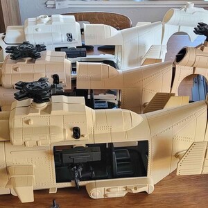 May include: Three unpainted plastic helicopter models in various stages of assembly. Two models are tan and one is white. Each helicopter features a cockpit, a main rotor assembly, a side door opening, and a tail section with a rear rotor mount.