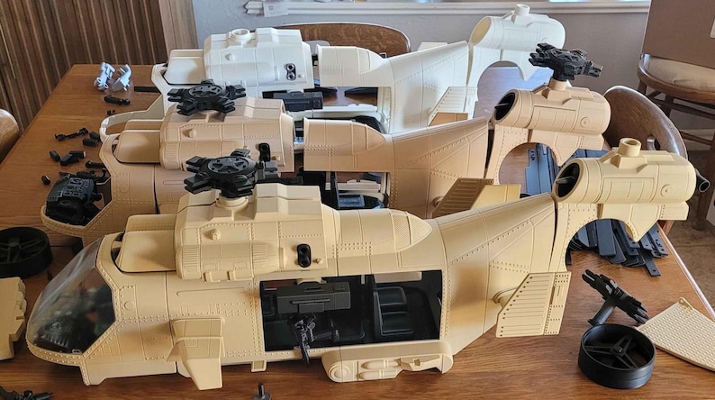 May include: Three unpainted plastic helicopter models in various stages of assembly. Two models are tan and one is white. Each helicopter features a cockpit, a main rotor assembly, a side door opening, and a tail section with a rear rotor mount.