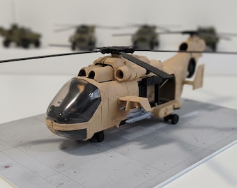 May include: Tan toy helicopter with black rotors and a clear cockpit. The model has open compartments and is positioned on a gray surface. Other toy helicopters are blurred in the background.