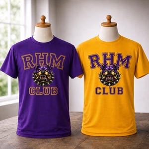 Op de afbeelding: Twee t-shirts op mannequins. E&eacute;n is paars, de andere is goudkleurig. Beide hebben de tekst "RHM CLUB" in gouden letters met een bulldog-afbeelding. De bulldog is paars en goud met een spijkerhalsband. De shirts worden op een houten tafel getoond.