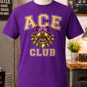 May include: A purple t-shirt featuring a bulldog graphic with a spiked collar. The text "ACE CLUB" is printed above and below the bulldog in gold and white. The t-shirt is displayed on a mannequin.