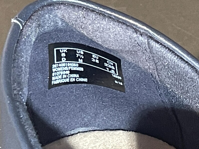 May include: Close-up of the inside of a dark blue shoe. A black label displays size information: UK 5, US 7&frac12; M, EU 38, and CM 23.5. The label also includes the text "WOMENS/FEMMES" and "MADE IN CHINA / FABRIQUE EN CHINE".