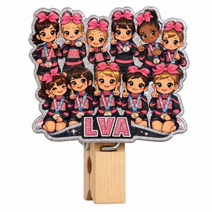 May include: A wooden clip featuring a glittery design of a cheerleading team. The team is wearing black and pink uniforms with pink bows. The letters "LVA" are displayed on the bottom of the design.