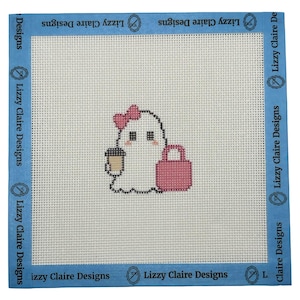 May include: A square needlepoint canvas featuring a white ghost character with a pink bow, holding a coffee cup and a pink handbag. The design is centered on a white grid with blue tape borders printed with the text Lizzy Claire Designs.