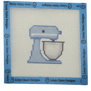 May include: A square needlepoint canvas featuring a light blue stand mixer design in the center. The canvas has a white grid pattern and is bordered by blue tape printed with the text Lizzy Claire Designs repeatedly along all four edges.