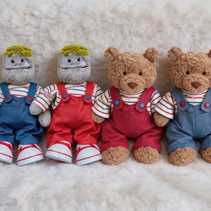 May include: Four plush dolls arranged in a row. The two on the left have grey rock-like heads with yellow hair, wearing striped shirts and overalls in blue and red. The two on the right are brown teddy bears wearing striped shirts and overalls.