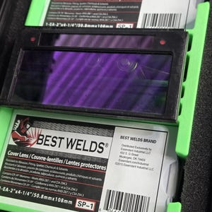 Puede incluir: Lentes de protecci&oacute;n para soldadura con una lente p&uacute;rpura en un marco negro. La marca "BEST WELDS" es visible, con texto en ingl&eacute;s, franc&eacute;s y espa&ntilde;ol. Las dimensiones son 50,8 mm x 108 mm.