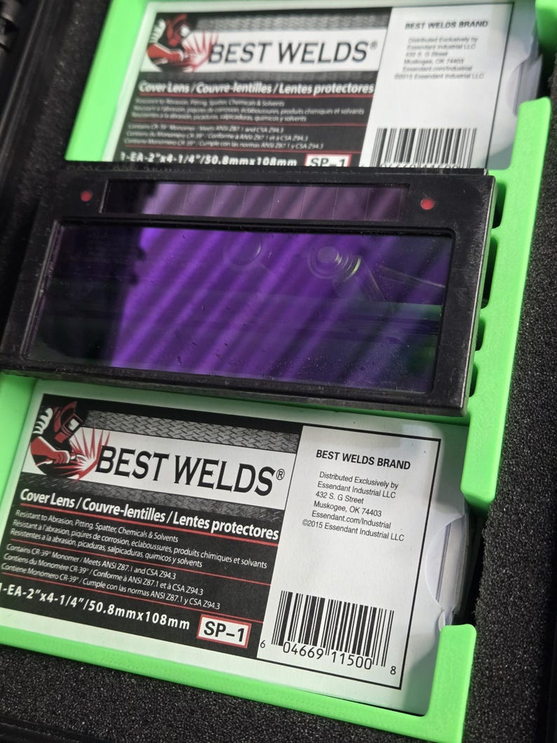 Puede incluir: Lentes de protecci&oacute;n para soldadura con una lente p&uacute;rpura en un marco negro. La marca "BEST WELDS" es visible, con texto en ingl&eacute;s, franc&eacute;s y espa&ntilde;ol. Las dimensiones son 50,8 mm x 108 mm.