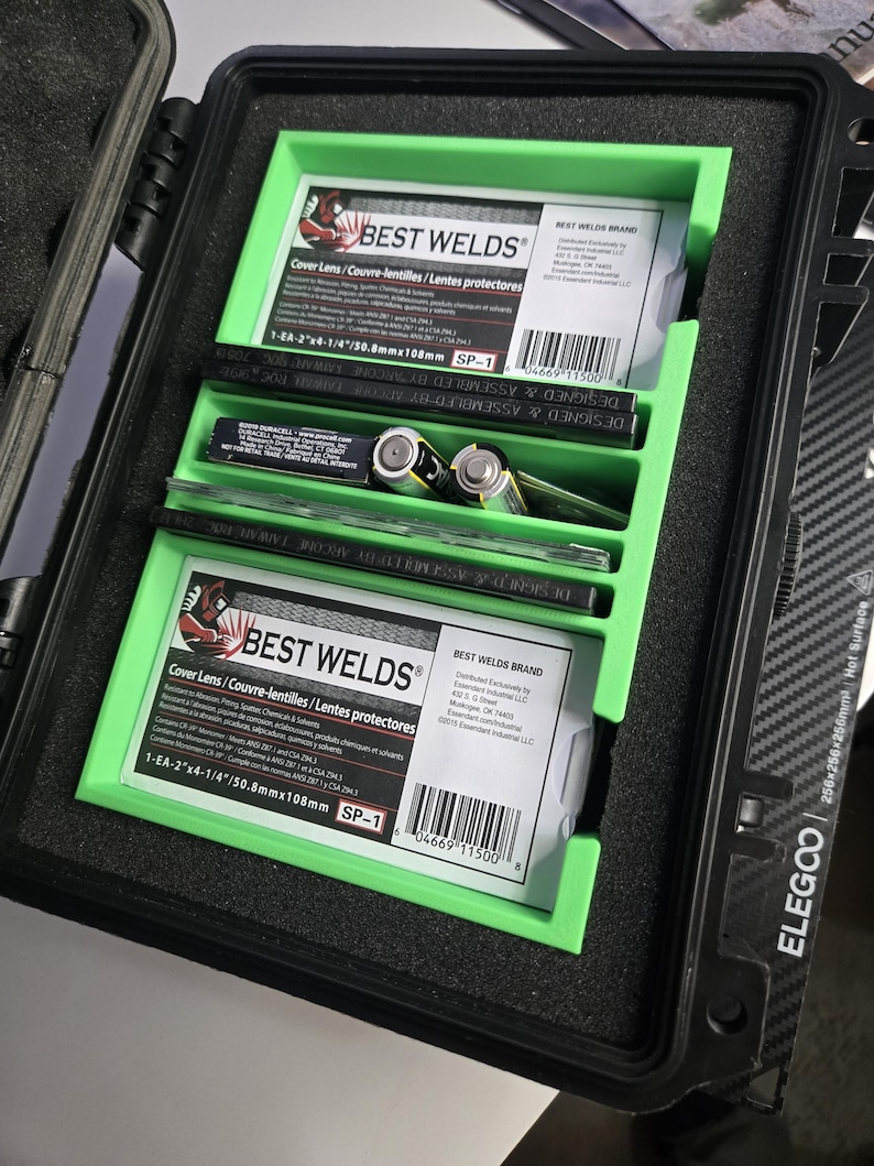 Puede incluir: Un estuche negro con interior verde, que contiene suministros de soldadura. El estuche contiene dos paquetes de lentes de protecci&oacute;n "BEST WELDS", junto con otras herramientas. Los paquetes tienen texto en ingl&eacute;s, franc&eacute;s y espa&ntilde;ol. El estuche est&aacute; etiquetado "ELEGCO".